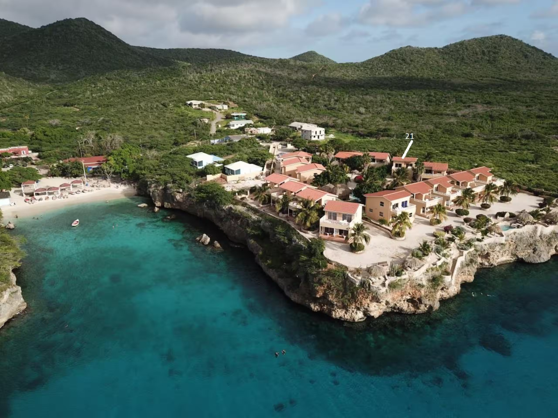 Aerial view of Playa Lagun and the Lagun Blou Resort hillside, with Grace & Waves, Huisje 21 marked among the bungalows above the turquoise cove